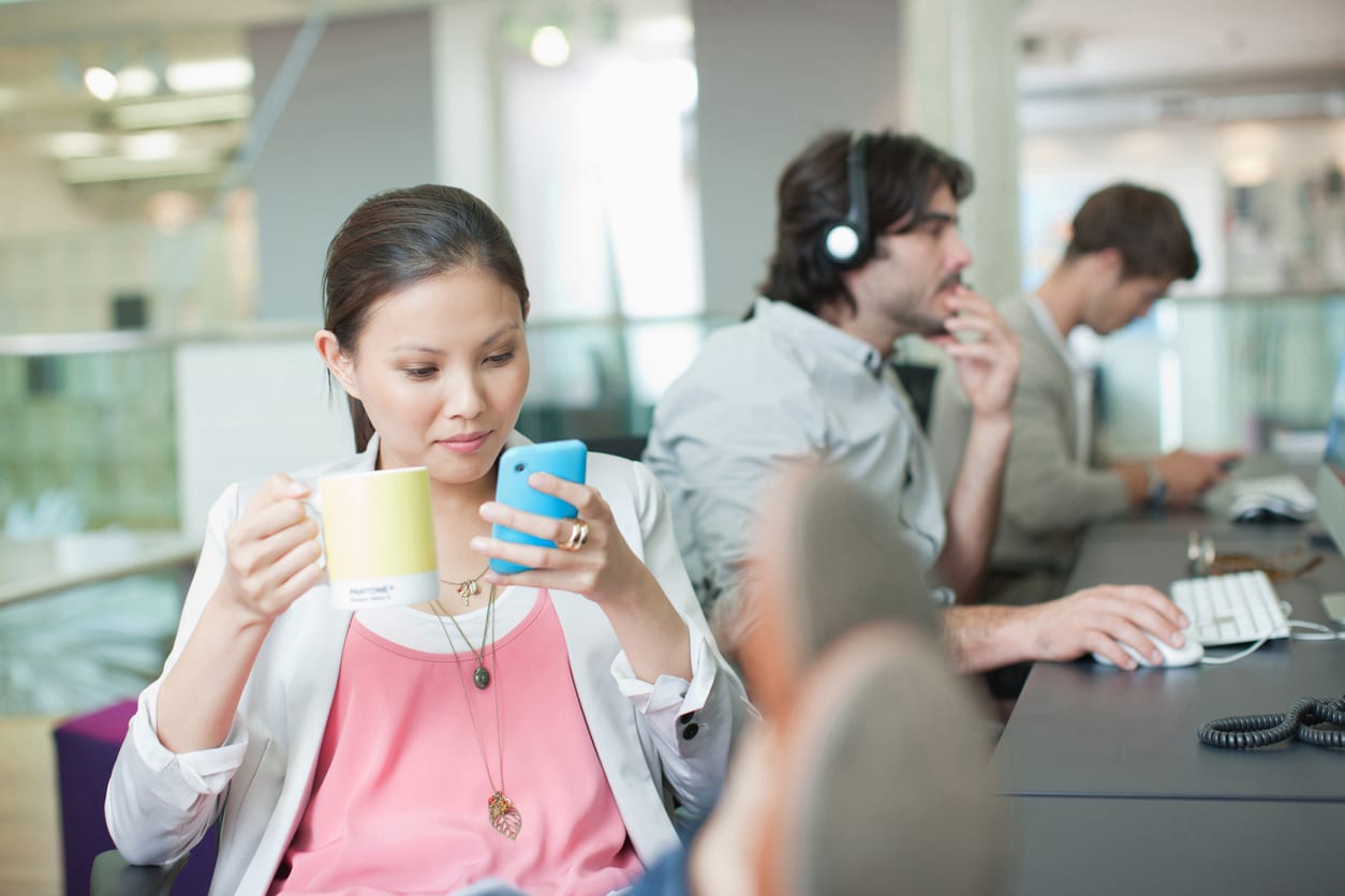 Businesswoman drinking coffee and text messaging