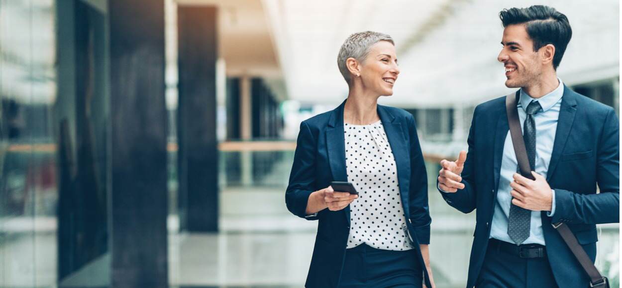 Two colleagues talking and walking in office building