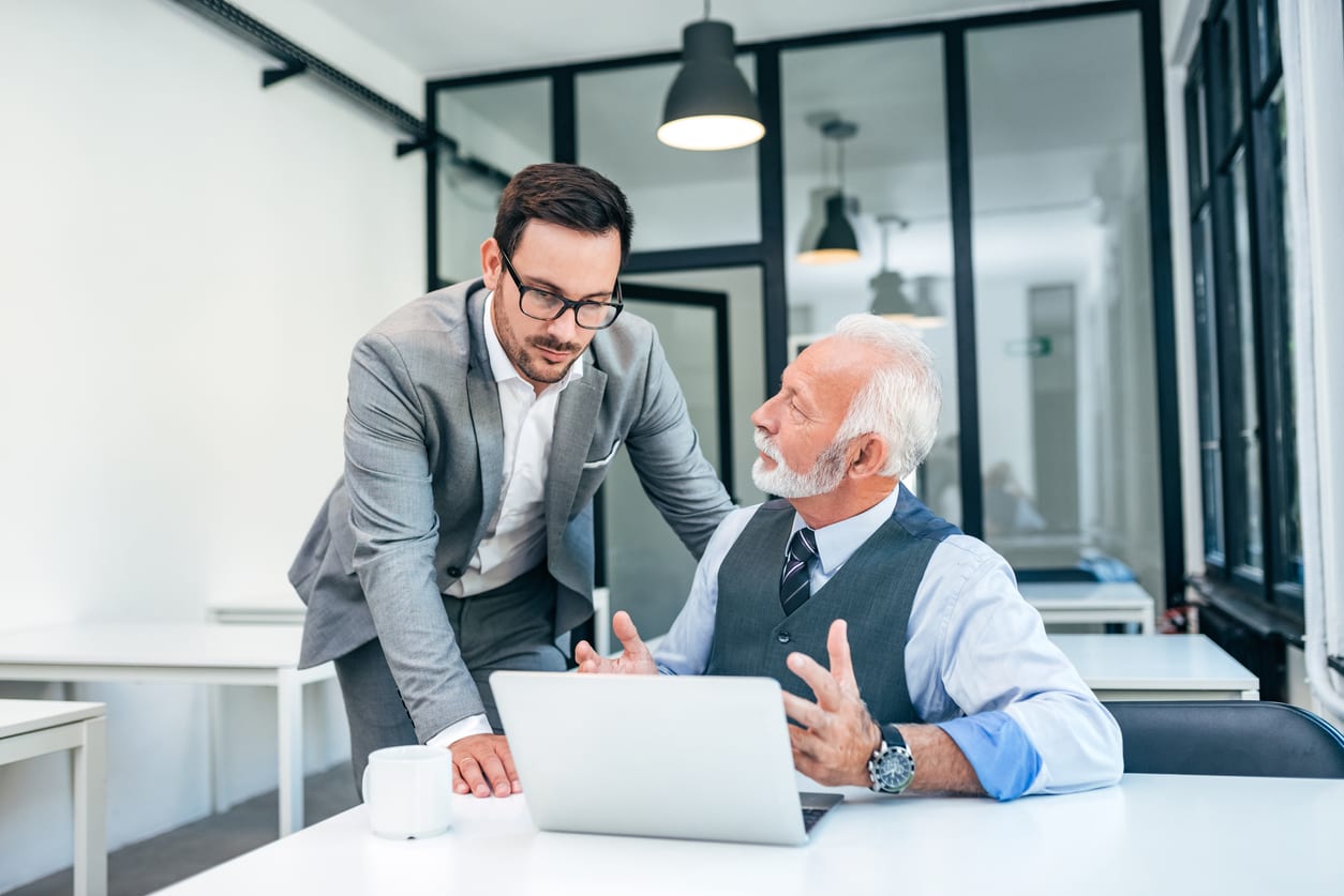 Young man discussing with boss or older employee in modern office.