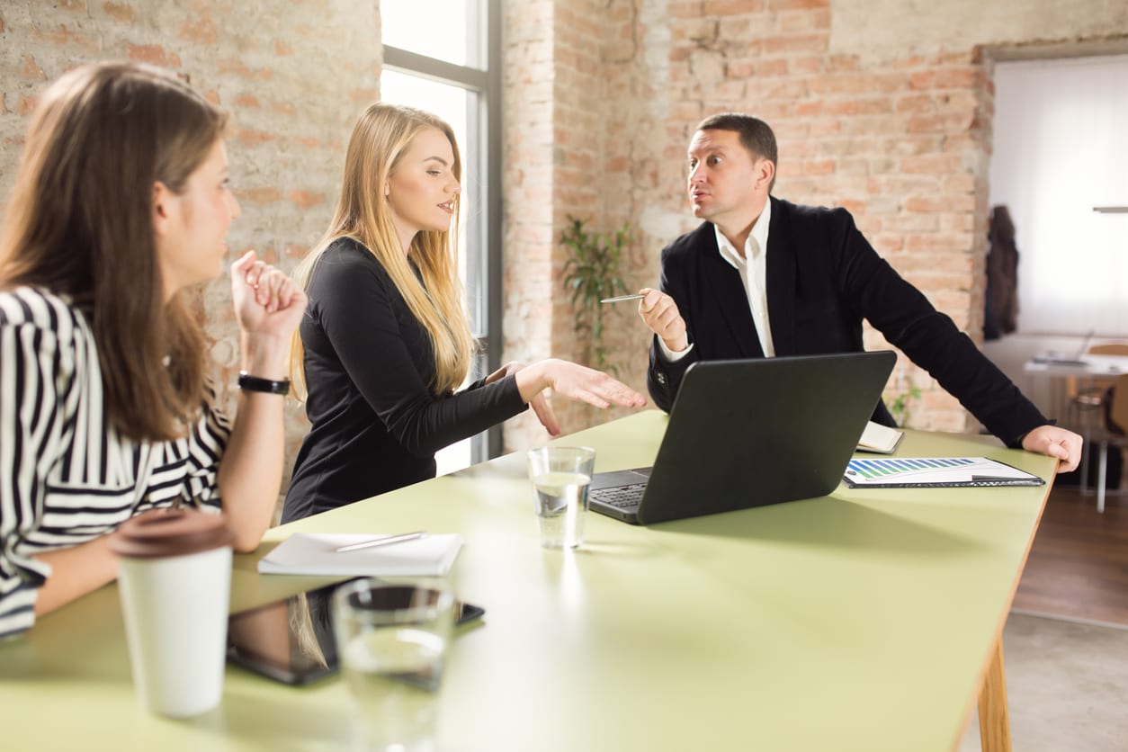 Angry manager scolding one of his subordinate while she is trying to explain the situation.