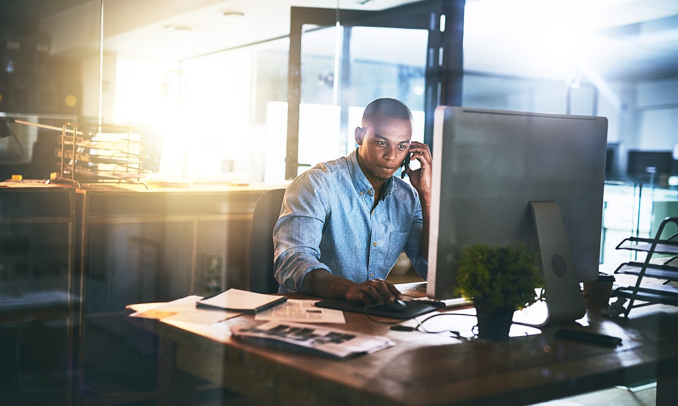 Shot of a young businessman using a mobile phone during a late night in a modern office