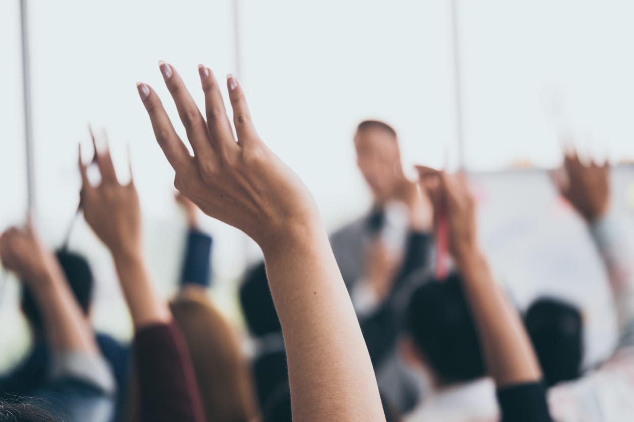 Employees in crowd raise hands