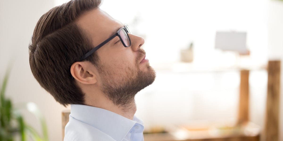 Headshot of man with eyes closed in an office