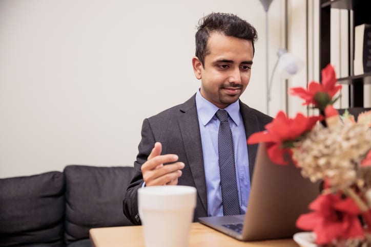 Work from home, Technology, Communication - Young man wearing suit and tie presenting his views over a video conference call.