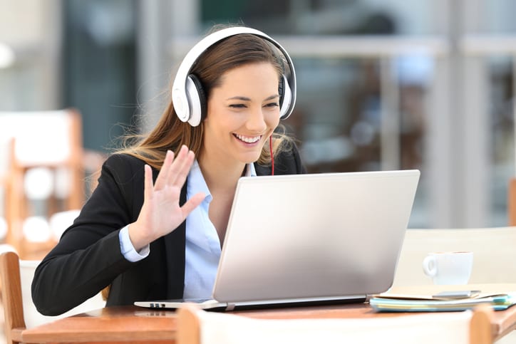 Executive having a video call with a laptop and headphones in a coffee shop