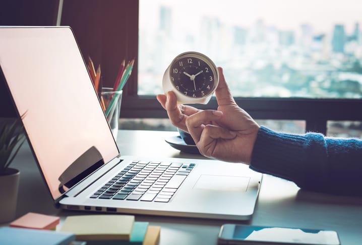 hand holding clock over laptop