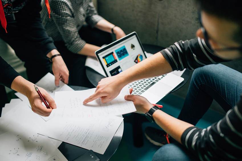 Cropped photo of employees discussing a report on a laptop and paper