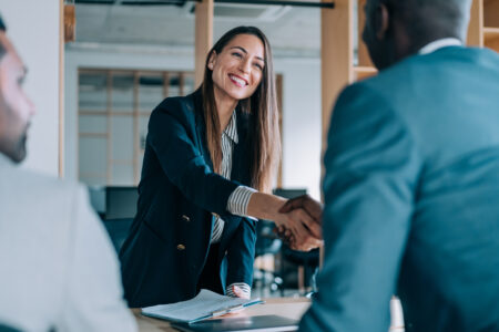 Business people shaking hands in the office. Group of business persons in business meeting. Three entrepreneurs on meeting in board room. Corporate business team on meeting in modern office. Female manager discussing new project with her colleagues. Company owner on a meeting with two of her employees in her office.