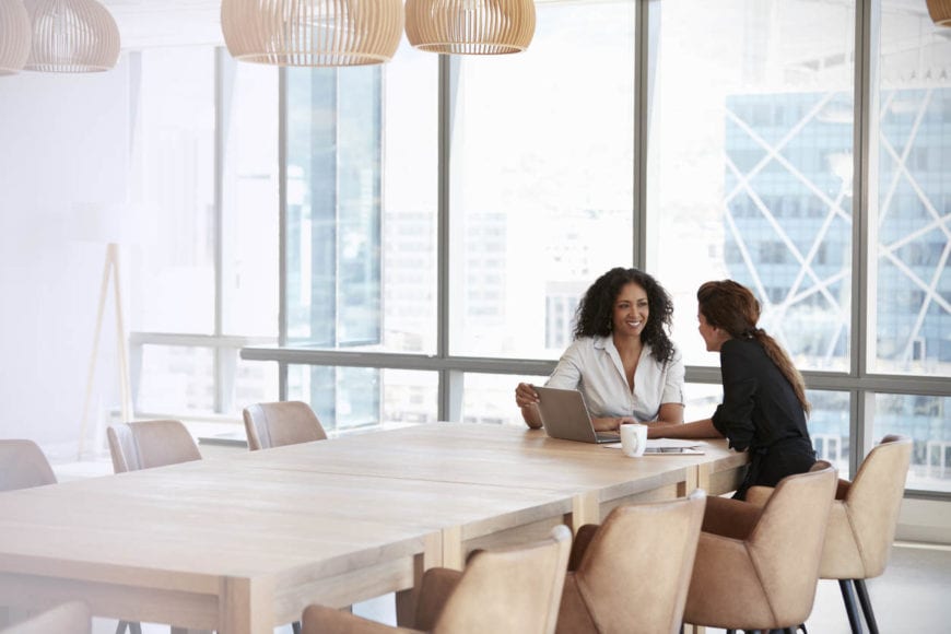 two women using laptop in boardroom meeting