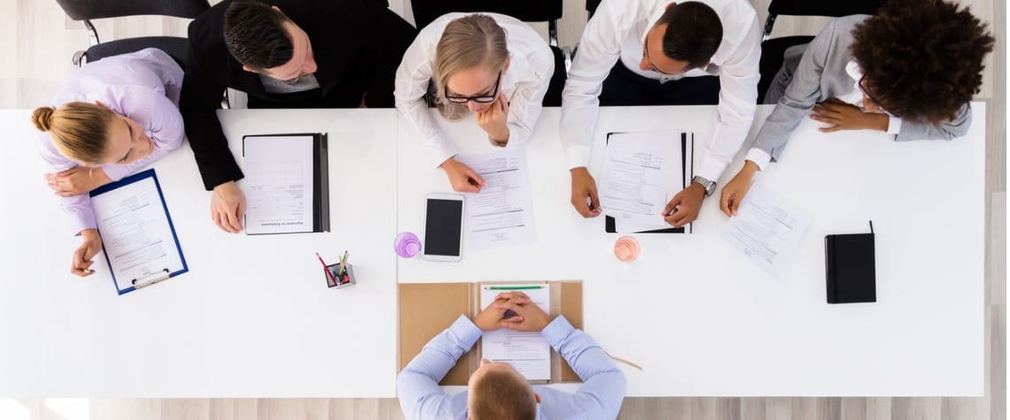 Business colleagues discuss over a while table, birds eye view