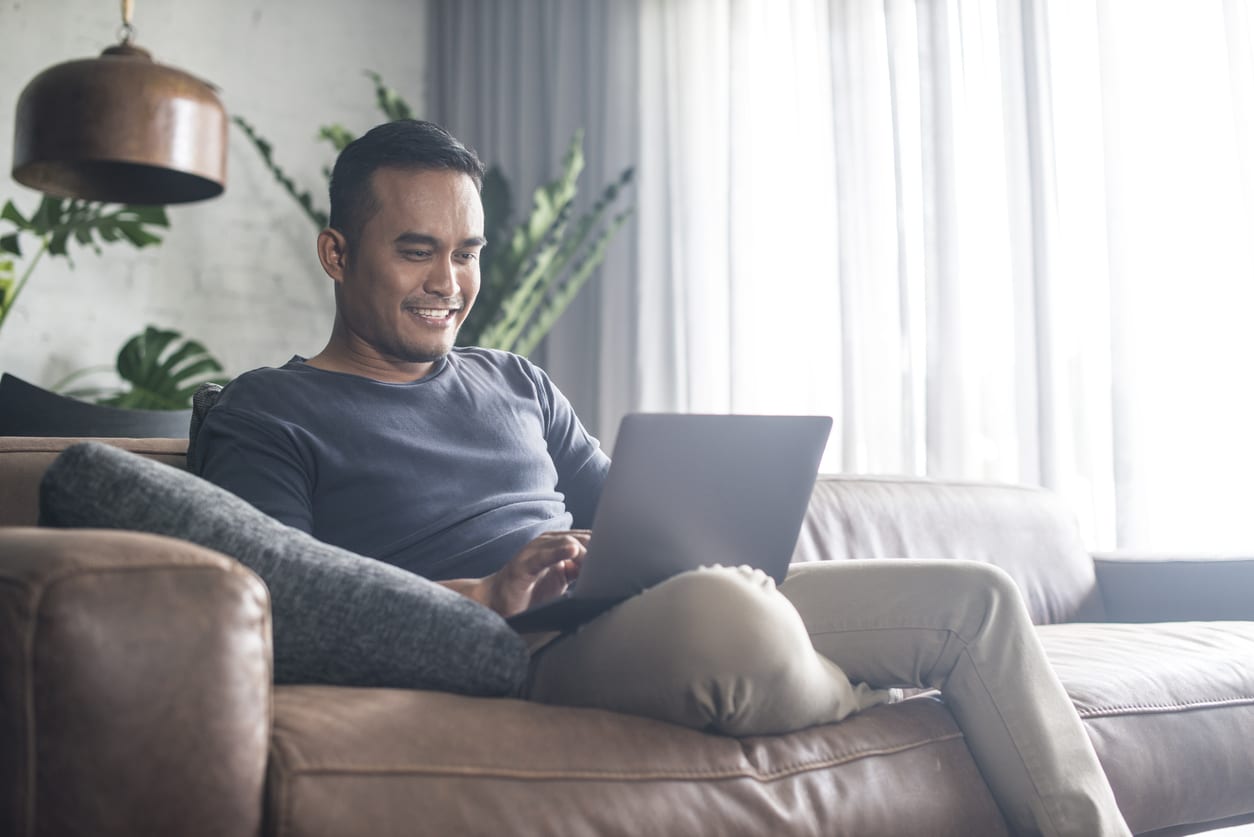 Young Asian man using the laptop in the living room.