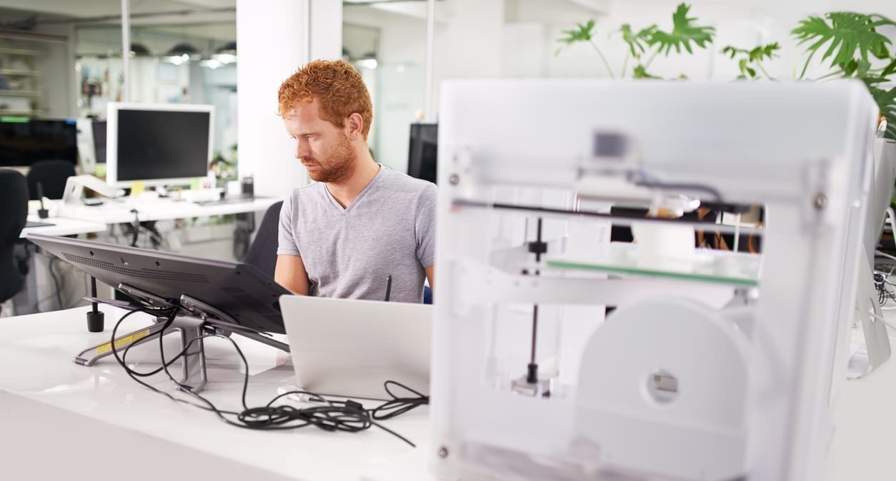 A shot of a young man printing his designs on a 3D printer