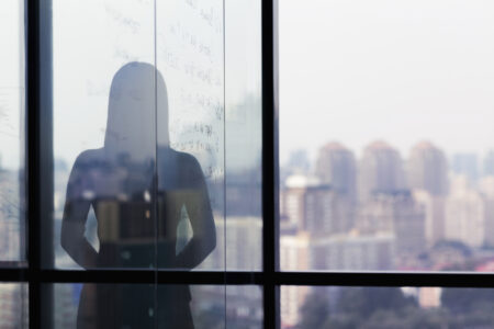 Silhouette shadow of woman looking at city from office