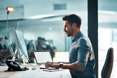 Shot of a young businessman using a computer at his desk in a modern office