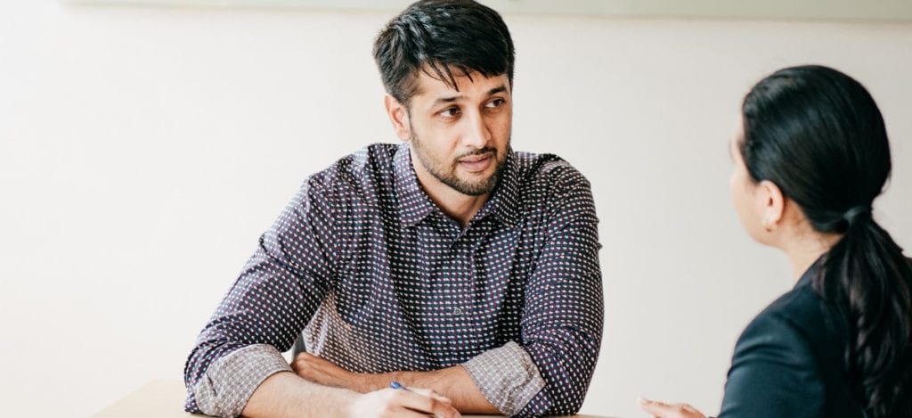 photo of man and women discussing something at a meeting table