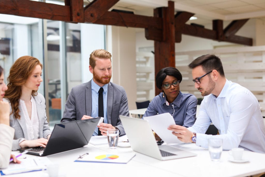 Group of business people is working on new business strategy with a financial analyst while analyzing financial chart during meeting in the office.