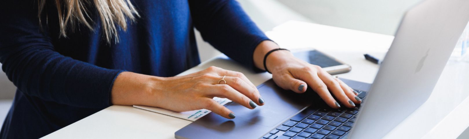 Cropped photo of woman's hands typing on a keyboard.