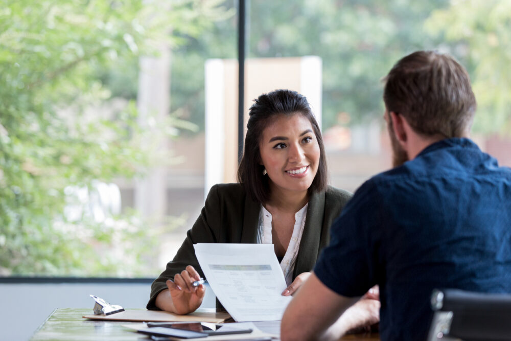 Male and female discussing something in a meeting whilst holding a piece of paper