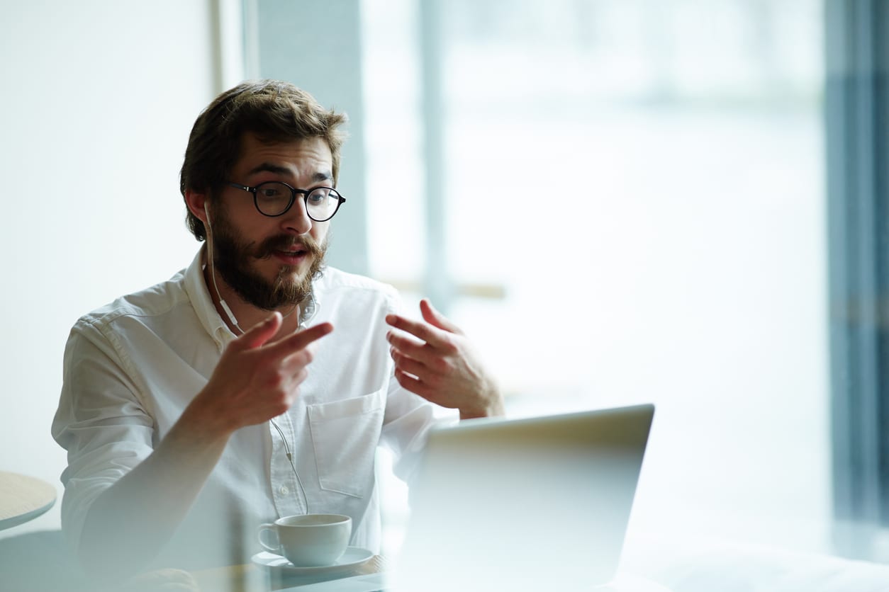 Man in white shirt and long beard on a video call in a bright office