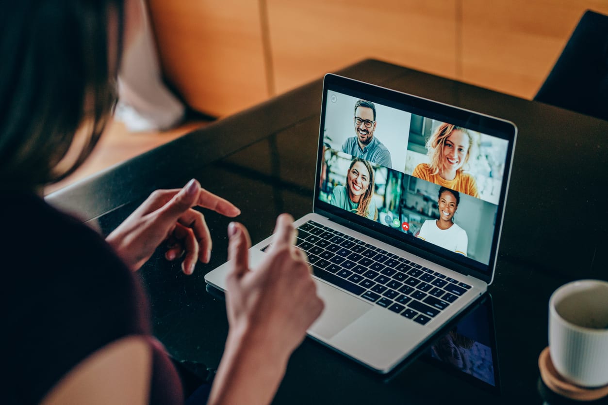 Shot of young woman talking to her friends in video call from home. Multi-ethnic group of people using laptop for a online meeting in video call. Friends having online conversation during quarantine.