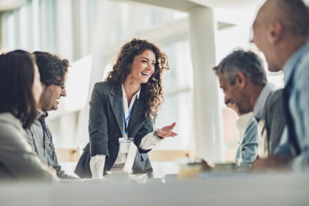 Young happy CEO communicating with her colleagues on a meeting in the office.