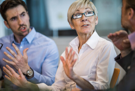 Senior businesswoman telling her colleagues to stop arguing on a meeting.