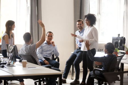 Diverse team in coworking space voting some colleagues agree raises hands. Positive black leader woman with creative group of businesspeople discussing sharing ideas together in office at meeting