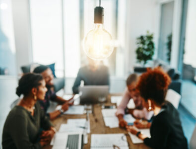 Shot of a group of young businesspeople having a meeting with a lightbulb in the foreground