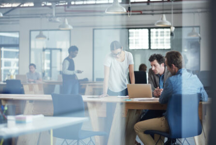 Shot of a group of colleagues talking together over a laptop in an office