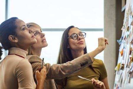 Businesswomen looking at fabric samples on presentation board. Confident female colleagues are working in textile factory. They are wearing smart casuals in office.