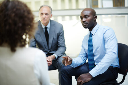 Attentive men listening to their female colleague during discussion at business training