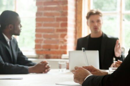 Serious business negotiators talking during stressful negotiations, focus on hands of businessman in tension making important decision, feeling pressure stress or being scolded by boss at meeting