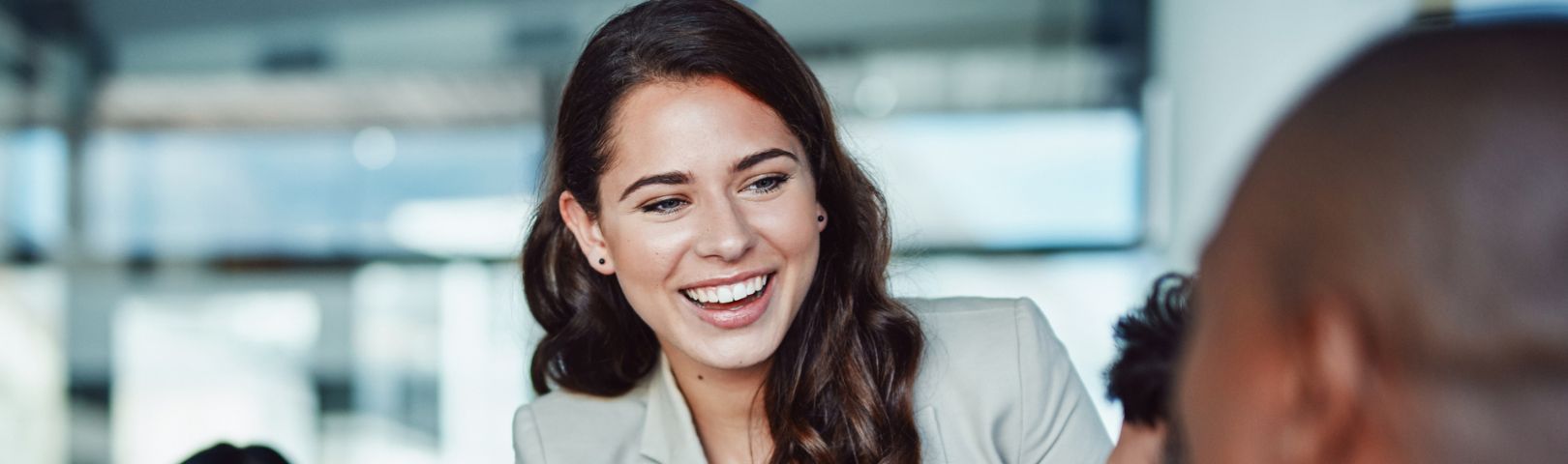 Cropped photo of a brown haired female smiling at male employees in an interview