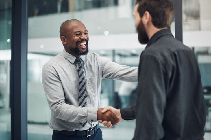 Two businessmen shaking hands in front of a glass office