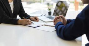 The manager is reading the resume and is interviewing the new employee. Negotiating business and signing a contract. Lawyer and legal advisor.