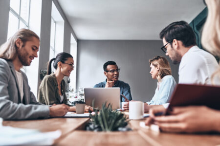 Group of young modern people in smart casual wear discussing business while working in the creative office