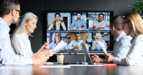 Employees in an office for a meeting on a call with other employees on the big screen