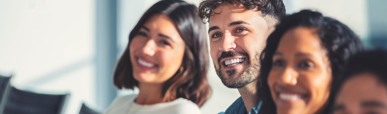 Two female and one male employee smiling towards the camera in a meeting