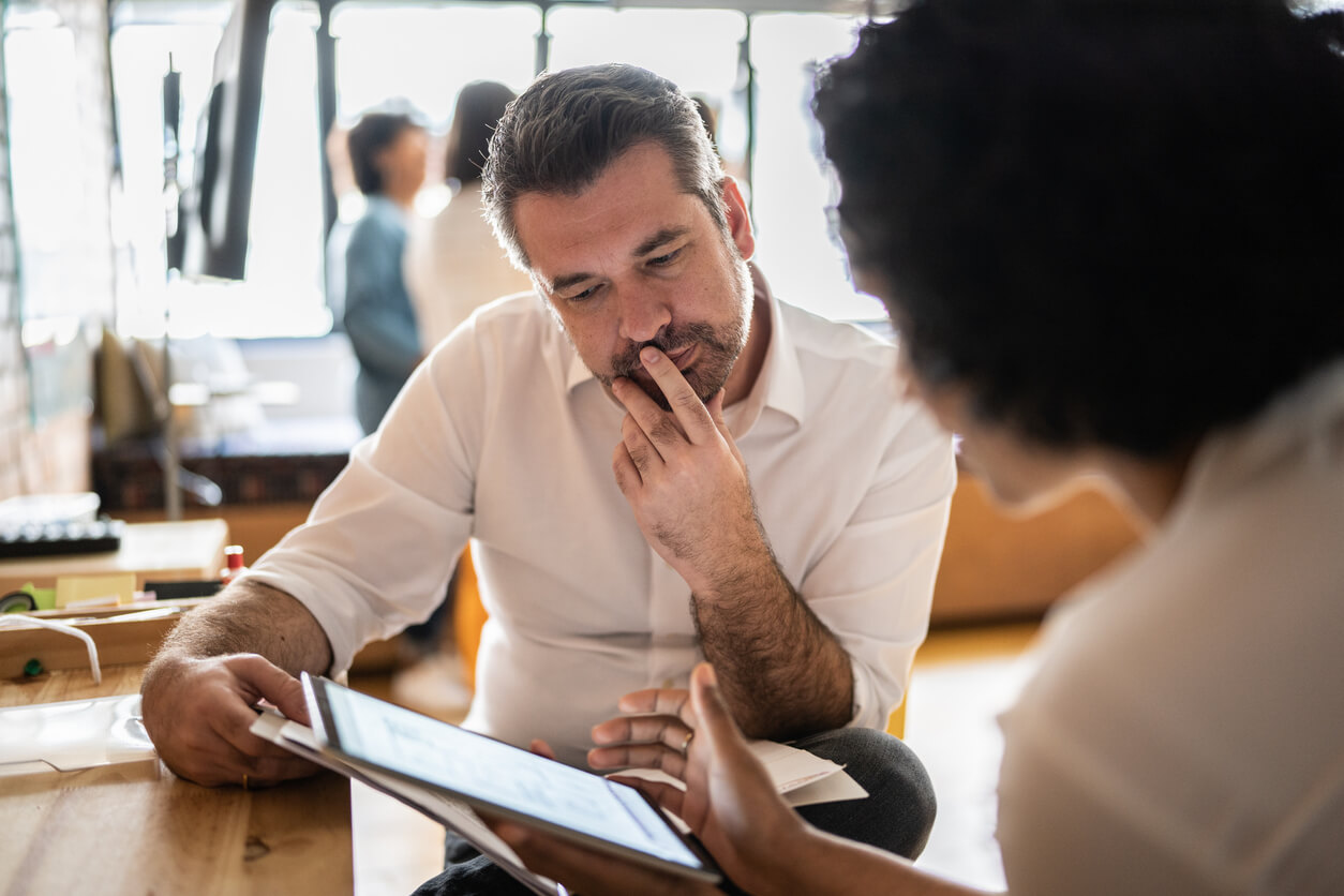 Male and female co worker looking at a tablet screen discussing something