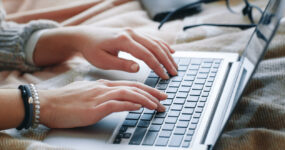 Cropped image of a woman's hands typing on a keyboard.