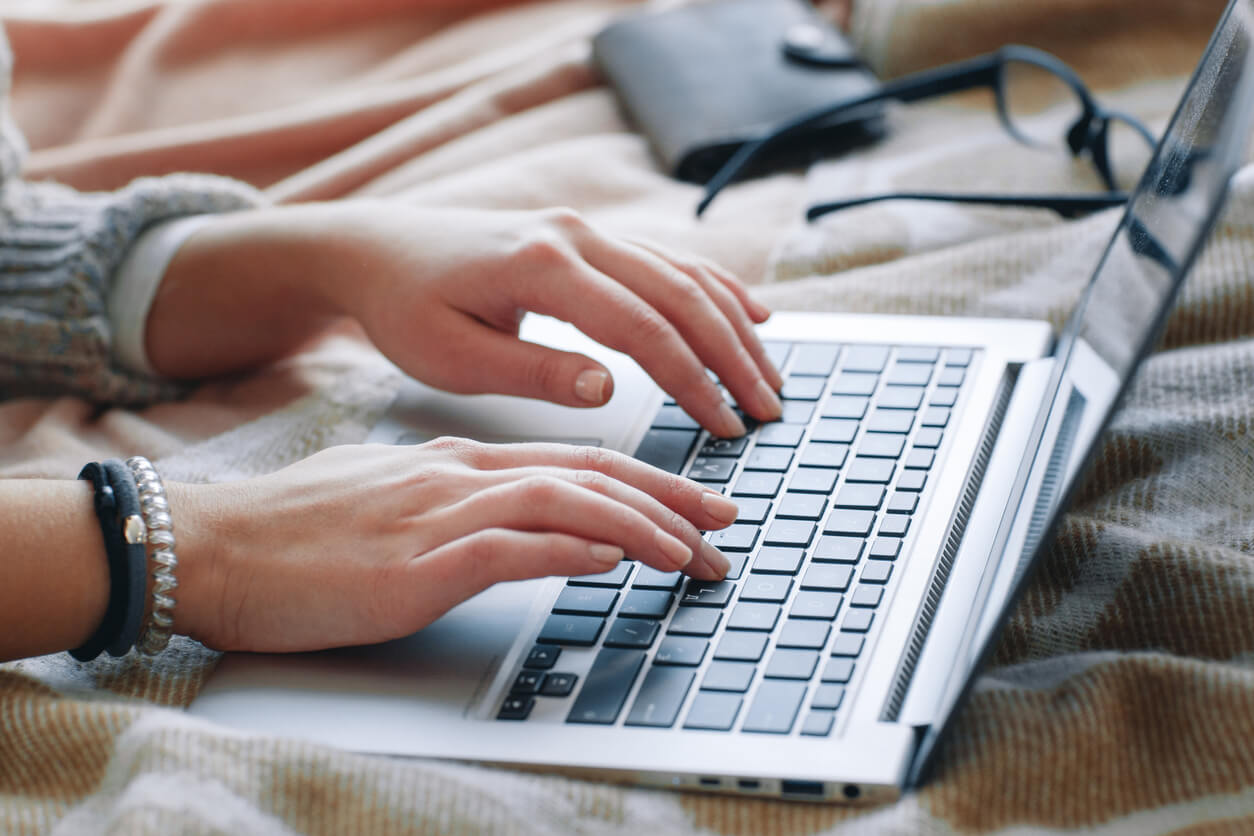 Cropped image of a woman's hands typing on a keyboard.