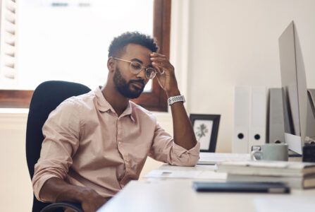 Shot of a young businessman looking tired while working in an office