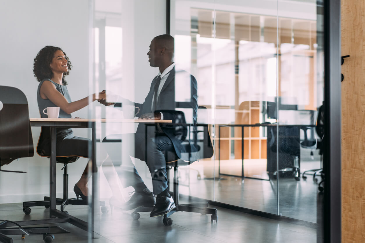 Two employees in an interview shaking hands.