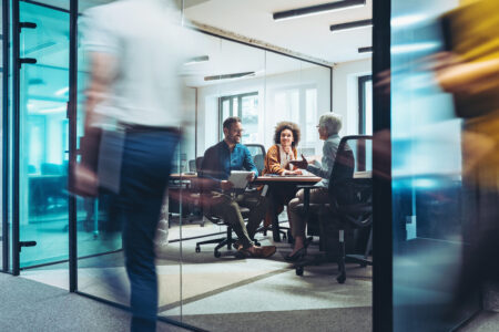 Group of business persons having a meeting in a closed glass conference room