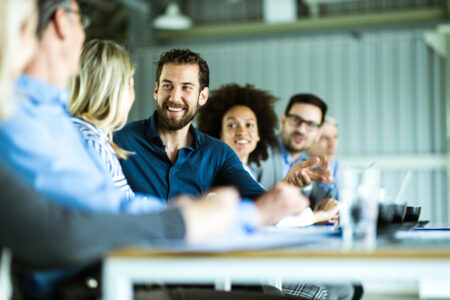 Happy business team having a talk during a meeting in the office. Focus is on young businessman.