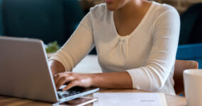 Cropped photo of women typing on keyboard whilst smiling