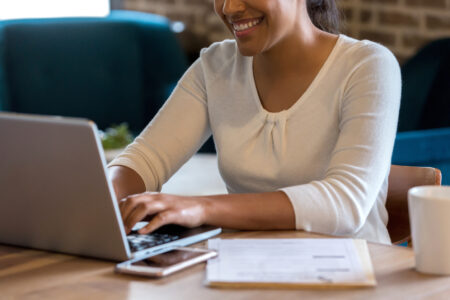 Cropped photo of women typing on keyboard whilst smiling