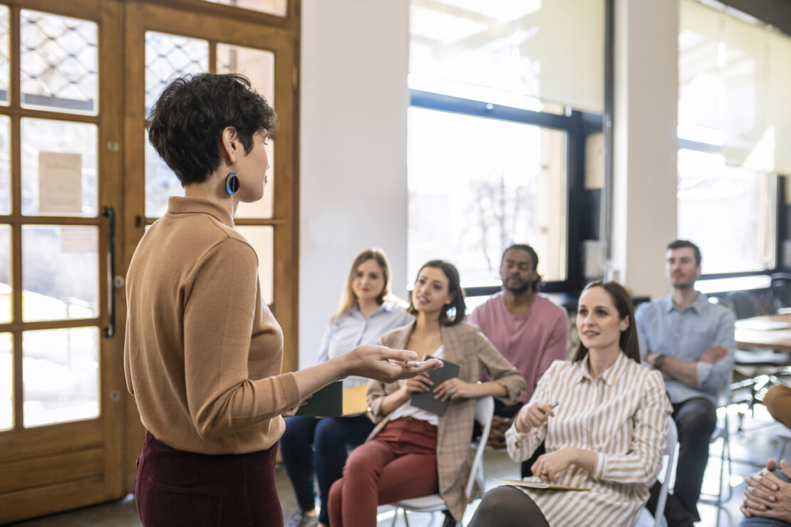 Employees sitting down listening to a female speak to them