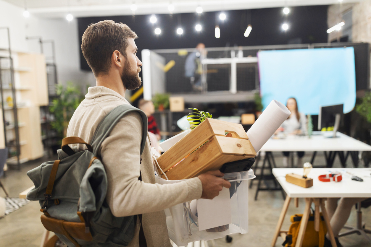 Man in grey jacket taking his stuff from work after resigning