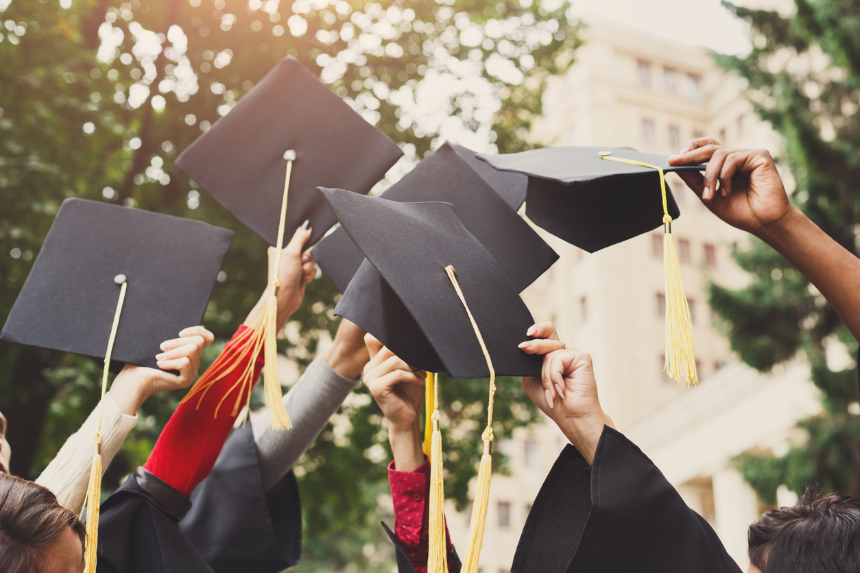 Students lifting up their graduation hats into the air